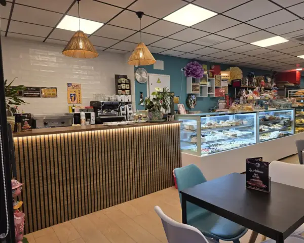 Barra de cafetería y vitrinas con mesas para desayunar, en La Artesana, Parla