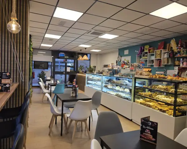 Comedor con mesas y vitrinas de pastelería, en La Artesana, Parla