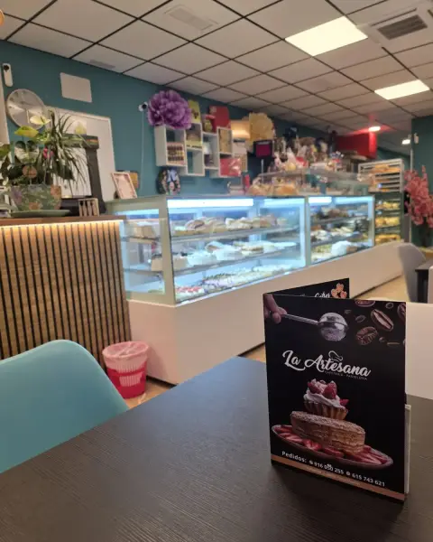 Interior con vitrinas y carta sobre mesa, en La Artesana, Parla