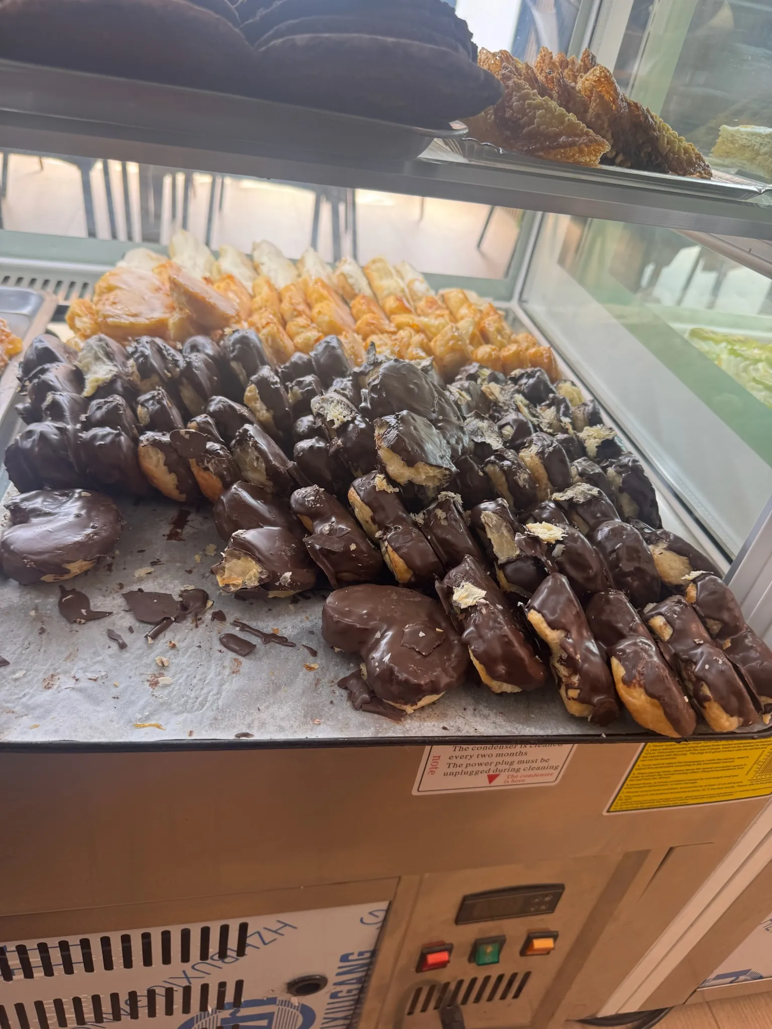 Mostrador lleno de pepitos de crema recién bañados en chocolate
