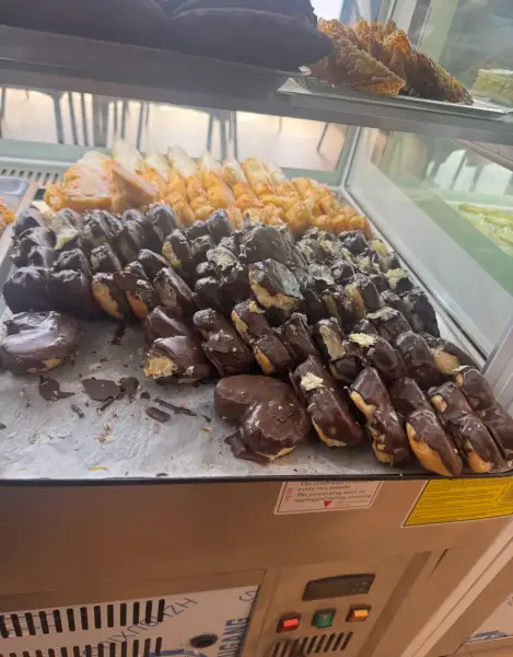 Pepitos y petisús de crema con chocolate en vitrina, en La Artesana, Parla