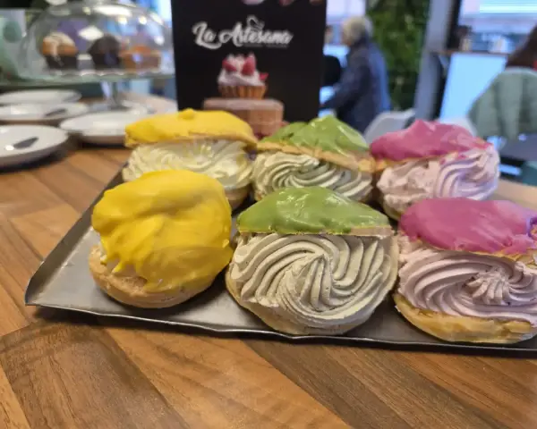 Petisús rellenos de crema de colores en bandeja, en La Artesana, Parla