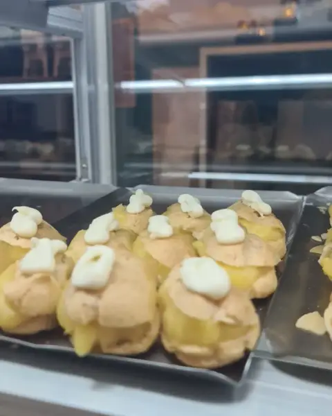 Profiteroles rellenos de crema con nata en vitrina, en La Artesana, Parla