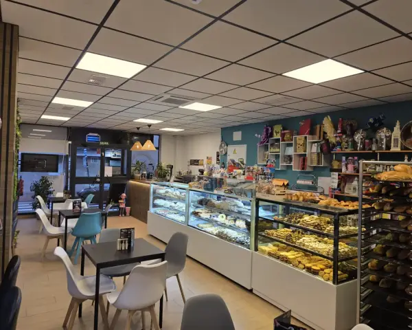 Salón interior con vitrinas y mesas de cafetería, en La Artesana, Parla