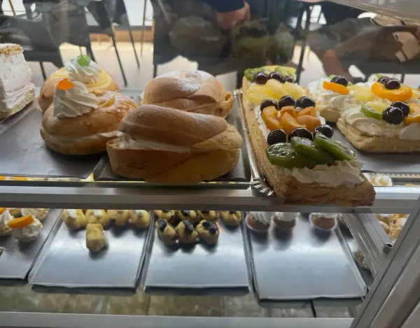 Suizos rellenos de nata y tartas de frutas en vitrina, en La Artesana, Parla