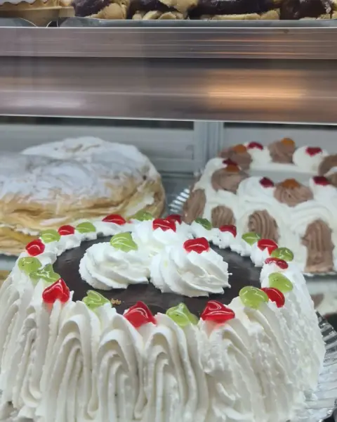 Tarta de chocolate con nata y guindas de colores, en La Artesana, Parla