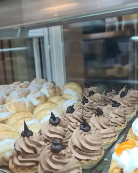 Tartaletas de chocolate y nata en vitrina, en La Artesana, Parla