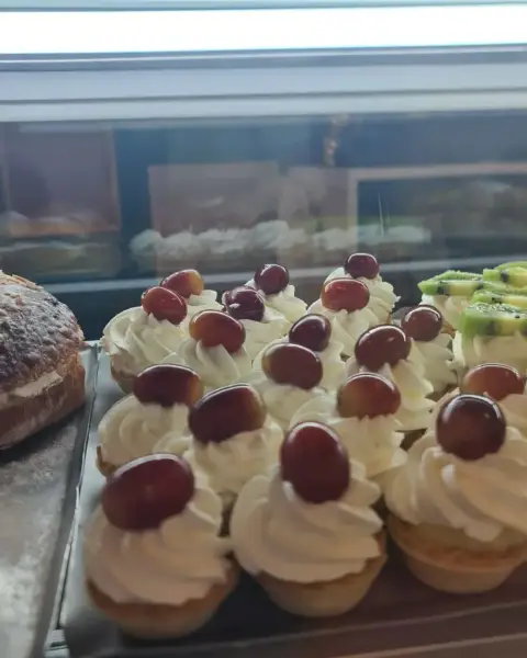 Tartaletas de nata con uvas rojas en vitrina, en La Artesana, Parla