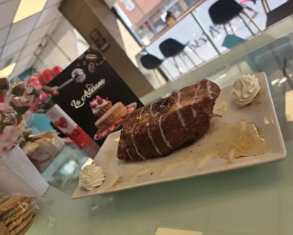 Porción de torrija caramelizada con nata en plato, en La Artesana, Parla