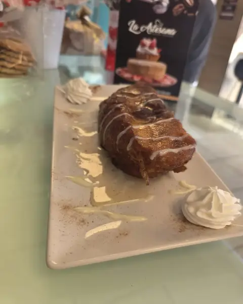 Torrija con miel y rosetones de nata en plato, en La Artesana, Parla
